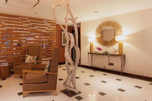 a living room with a chair and a mirror at The Somerset Hotel in Male City