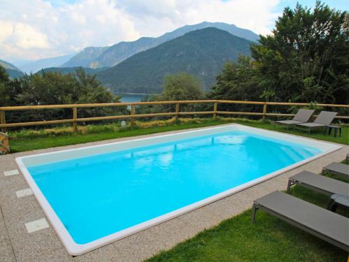 a large blue swimming pool with mountains in the background at Apartment Europa-1 by Interhome in Ledro