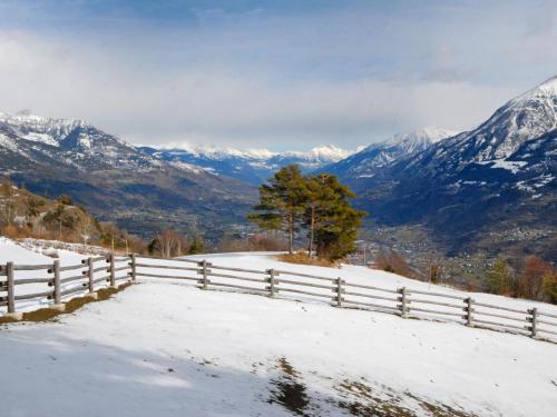 a fence on a snow covered hill with mountains at Apartment Renard by Interhome in Sarre