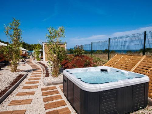 a hot tub in a backyard with a fence at Holiday Home Camping Kastanija-1 by Interhome in Novigrad Istria