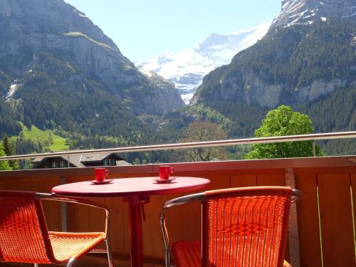 d'une table et de chaises sur un balcon avec vue sur les montagnes. dans l'établissement Apartment Chalet Almisgässli by Interhome, à Grindelwald