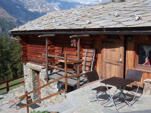 a log cabin with two chairs and a table at Studio Ancienne Bergerie Studio 2 by Interhome in Valtournenche