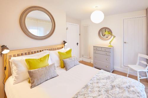 una camera da letto con un letto bianco con cuscini gialli e uno specchio di Host & Stay - The Old Dairy a Masham