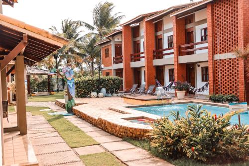 a resort with a swimming pool in front of a building at Pousada e Chale Porto Paraiso in Porto Seguro