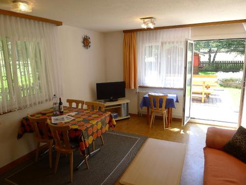 ein Wohnzimmer mit einem Tisch, Stühlen und einem TV in der Unterkunft Apartment Amara by Interhome in Saas-Fee