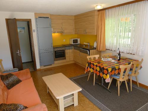 ein Wohnzimmer mit einer Küche und einem Tisch mit Stühlen in der Unterkunft Apartment Amara by Interhome in Saas-Fee
