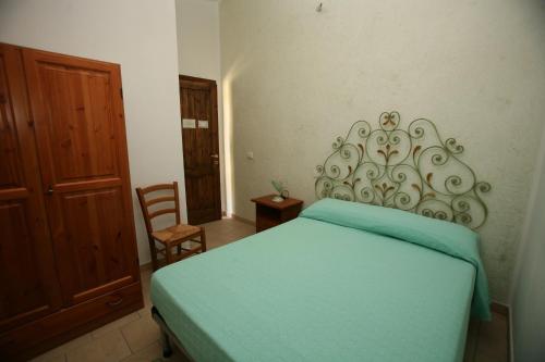 1 dormitorio con cama verde y puerta de madera en Agriturismo Ticci, en Seùlo