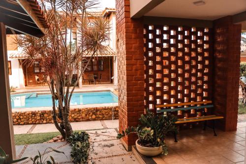 a pool with a bench next to a brick wall at Pousada e Chale Porto Paraiso in Porto Seguro