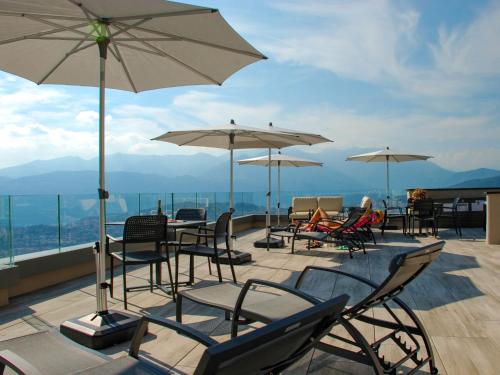 een groep stoelen en tafels met parasols op een dak bij Apartment Aldesago Monte Brè - Utoring-28 by Interhome in Viganello