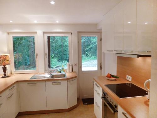 una cocina con armarios blancos, fregadero y ventanas en Holiday Home Leubach by Interhome en Schiltach