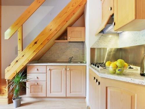 a kitchen with white cabinets and a staircase with wooden ceilings at Apartment Penia 2-1 by Interhome in Penia