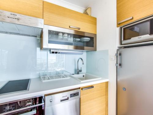 une cuisine avec des armoires en bois et un réfrigérateur en acier inoxydable dans l'établissement Apartment Les Rivages de Rochelongue-4 by Interhome, au Cap d'Agde