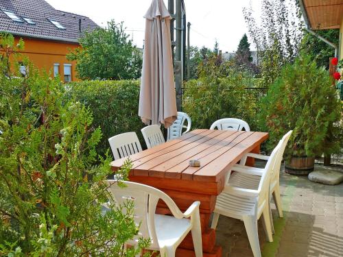 バラトンマーリアフュルドゥーにあるHoliday Home Colore by Interhomeの木製テーブル(白い椅子、傘付)