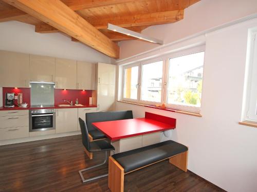 una piccola cucina con tavolo e sedie rossi di Apartment Am Bärenkopf-4 by Interhome a Maurach