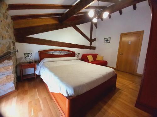 アルサスアにあるErrotazar apartamento rural Pのベッドルーム1室(大型ベッド1台、赤い椅子付)