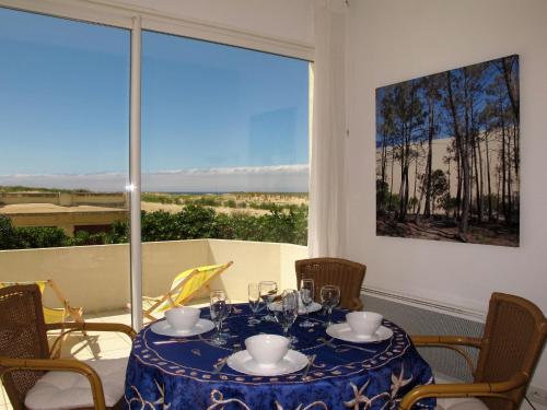 a table with a blue table cloth and chairs and a window at Apartment Capama-1 by Interhome in Mimizan-Plage