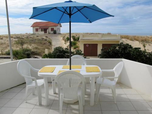 a white table and chairs with a blue umbrella at Apartment Capama-1 by Interhome in Mimizan-Plage