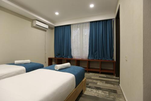 a bedroom with two beds and a window with blue curtains at Borjomi UnderWood in Borjomi