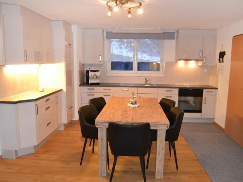 uma cozinha com uma mesa de madeira e cadeiras pretas em Apartment Bennico by Interhome em Emmetten