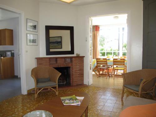 a living room with a fireplace and a table and chairs at Holiday Home Les Bruyères by Interhome in Mimizan-Plage