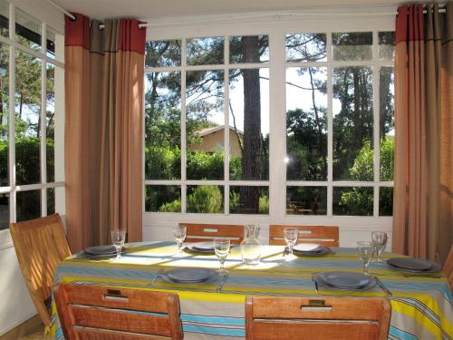a dining room table with chairs and a large window at Holiday Home Les Bruyères by Interhome in Mimizan-Plage