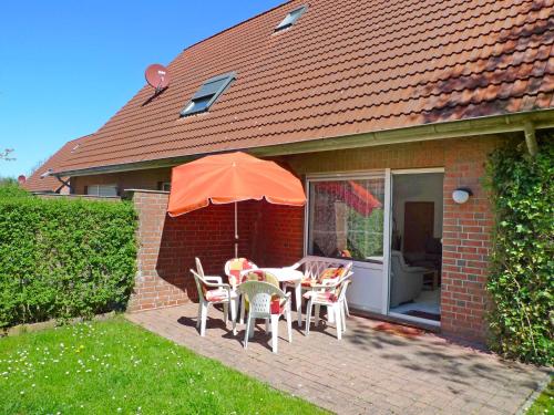 a patio with a table and chairs and an umbrella at Holiday Home Robbe by Interhome in Norddeich