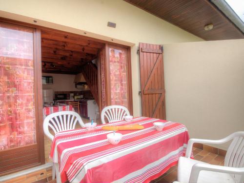 a table with three white chairs and a red and white table cloth at Holiday Home Sicard-10 by Interhome in Mimizan-Plage