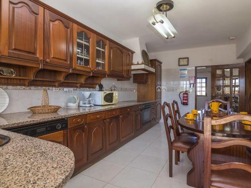 a kitchen with wooden cabinets and a table with chairs at Villa Villa Quinta do Sol by Interhome in Armação de Pêra
