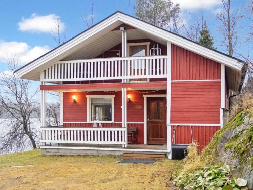 ein rotes Haus auf einem Hügel mit einer Veranda in der Unterkunft Holiday Home Pesäkolo by Interhome in Kiviperä