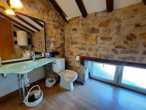a bathroom with a sink and a toilet and a stone wall at Errotazar apartamento M in Alsasua