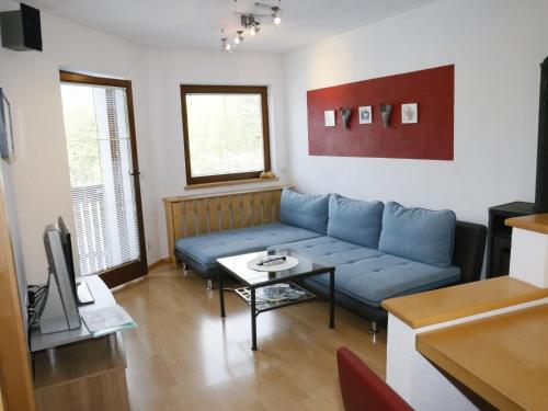 a living room with a blue couch and a table at Apartment Camping Rossbach-2 by Interhome in Nassereith