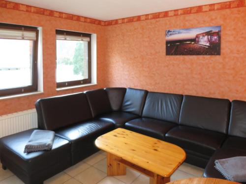 ein Wohnzimmer mit einem schwarzen Ledersofa und einem Tisch in der Unterkunft Apartment Ferienapartments Adenau-2 by Interhome in Adenau