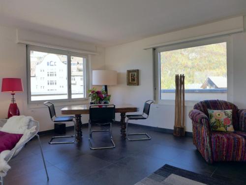ein Wohnzimmer mit einem Tisch und Stühlen sowie 2 Fenstern in der Unterkunft Apartment Panorama by Interhome in Interlaken
