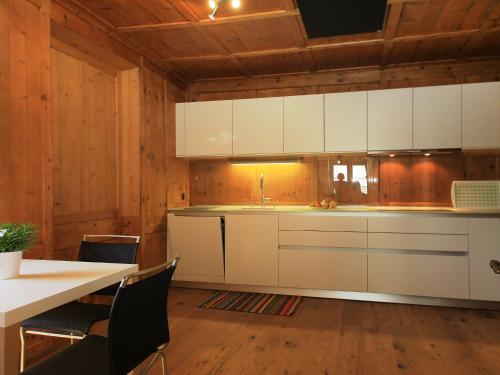 a kitchen with white cabinets and a table and chairs at Apartment Vitg Grond A2 by Interhome in Flims