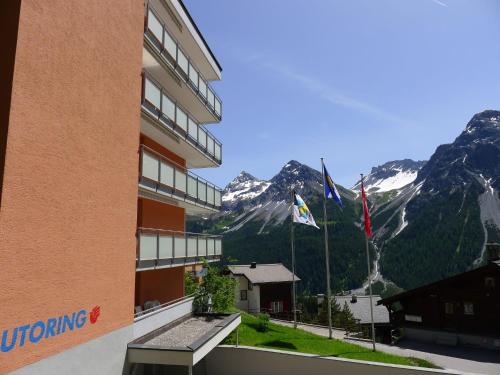 a building with two flags and mountains in the background at Apartment Promenade - Utoring-55 by Interhome in Arosa