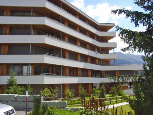 a large white building with mountains in the background at Apartment Promenade Wohnung 21 by Interhome in Davos
