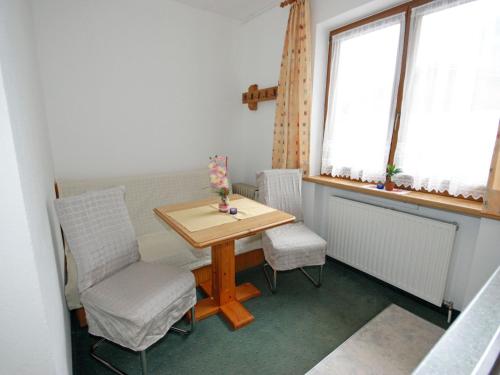 stół i krzesła w pokoju z dwoma oknami w obiekcie Apartment Falkner-1 by Interhome w mieście Oberlängenfeld
