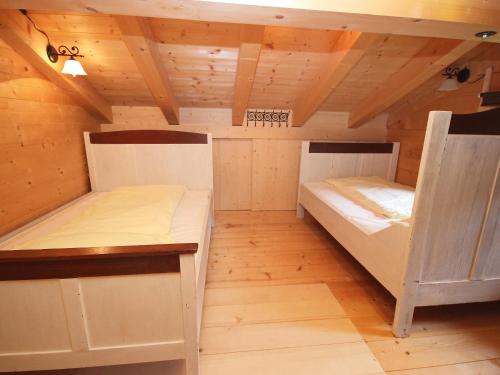 two beds in a room with wooden floors and ceilings at Chalet Königsleiten 3 by Interhome in Königsleiten