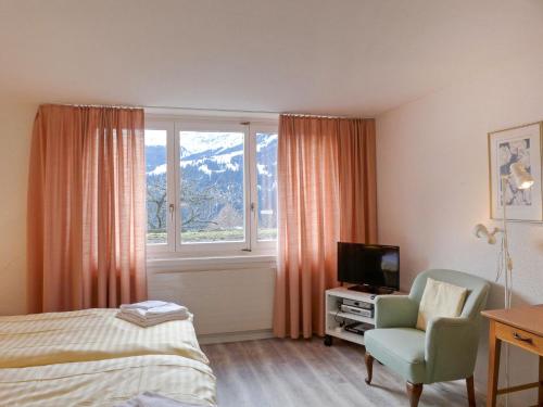 ein Schlafzimmer mit einem Bett, einem Stuhl und einem Fenster in der Unterkunft Apartment Helene Apt- Hella by Interhome in Wengen
