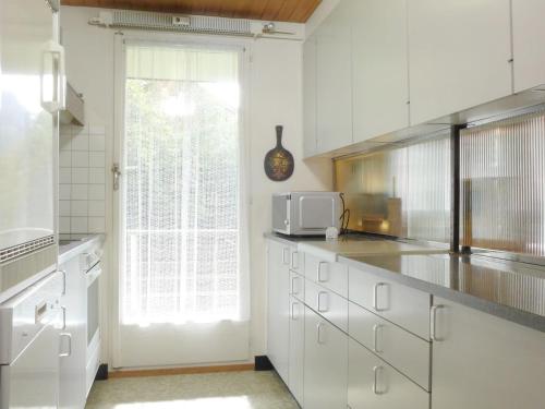 ヴェンゲンにあるApartment Zur Linde by Interhomeの白いキャビネットと窓付きのキッチン