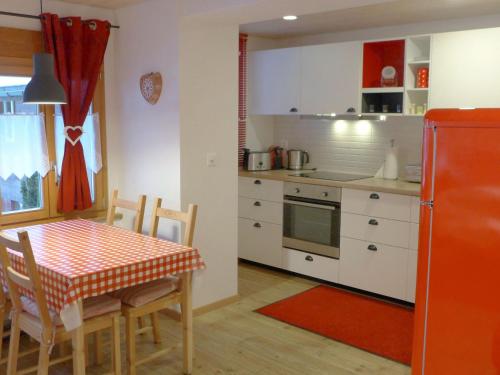 eine Küche mit einem Tisch und einem roten Kühlschrank in der Unterkunft Apartment Chalet Almisräba by Interhome in Grindelwald