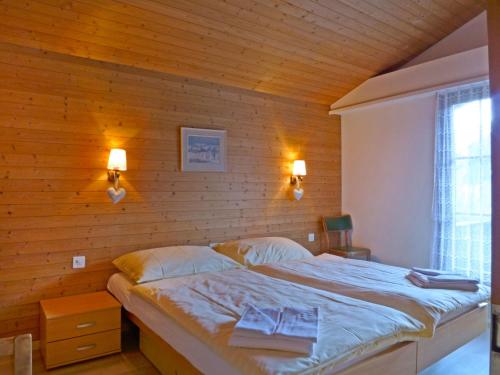 a bed in a bedroom with a wooden wall at Apartment Bergkristall by Interhome in Wengen