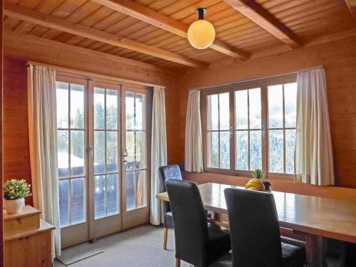 a dining room with a table and chairs and windows at Chalet Arche by Interhome in Wengen