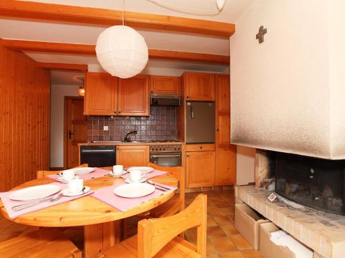 Apartment Zodiaque RS 4 by Interhome في أوفروناز: مطبخ مع طاولة خشبية ومدفأة كبيرة