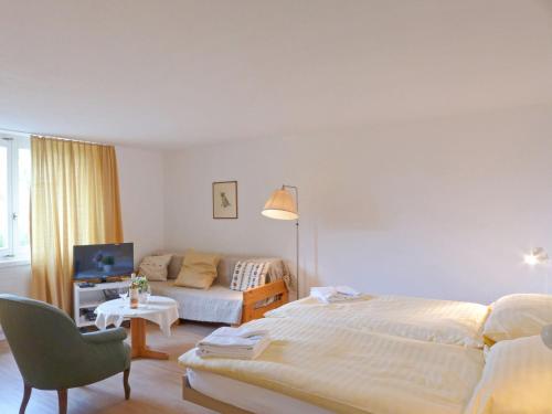 ein weißes Schlafzimmer mit einem Bett und einem Sofa in der Unterkunft Studio Helene Studio Christel by Interhome in Wengen