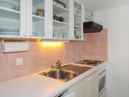 eine Küche mit einer Spüle aus Edelstahl und weißen Schränken in der Unterkunft Studio Helene Studio Christel by Interhome in Wengen
