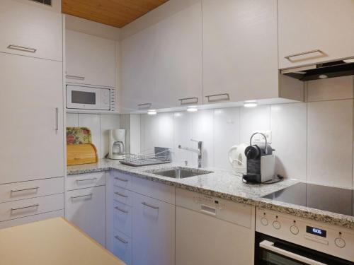a white kitchen with a sink and a microwave at Apartment Schweizerhof-2 by Interhome in Wengen