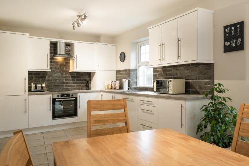 a kitchen with white cabinets and a wooden table at Escape Ordinary at Devenish Manor in Enniskillen