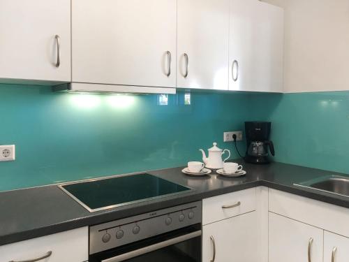 a kitchen with white cabinets and a stove top oven at Holiday Home Zum munteren Eichhörnchen by Interhome in Dittishausen