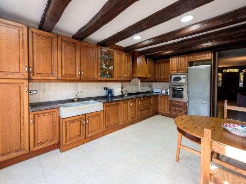 ラ・セウ・ドゥルジェイにあるHoliday Home Can Oscar by Interhomeの木製キャビネットとテーブル付きの広いキッチンが備わります。